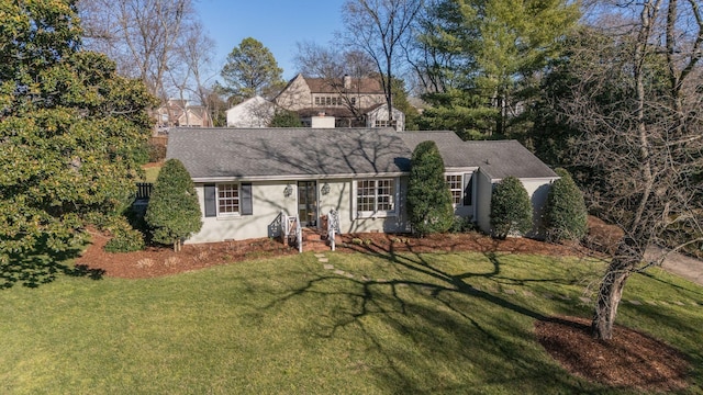 view of front facade featuring a front yard, roof with shingles, and stucco siding