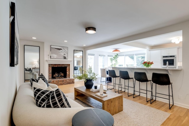 living area featuring recessed lighting, a fireplace, light wood-type flooring, and baseboards