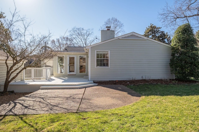 back of house with a chimney, a patio, a wooden deck, and a yard