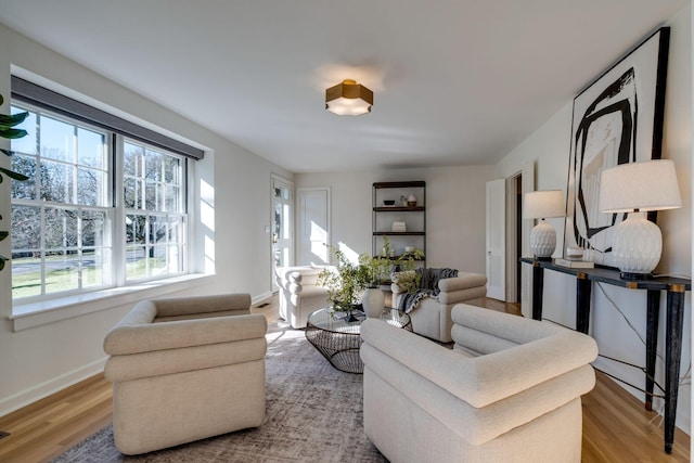 living area featuring plenty of natural light, light wood-style flooring, and baseboards