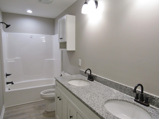 full bathroom featuring wood finished floors, toilet, bathtub / shower combination, and a sink