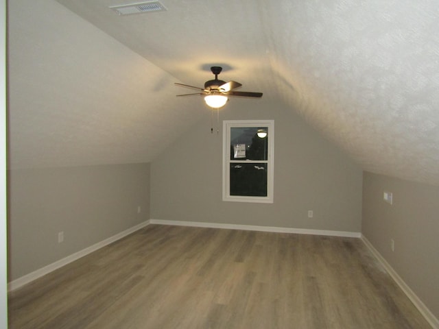 bonus room with visible vents, a textured ceiling, baseboards, and wood finished floors