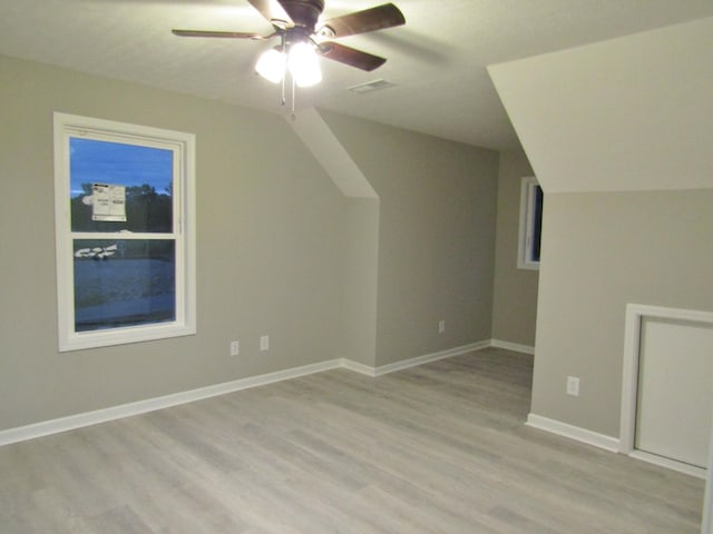 additional living space with visible vents, ceiling fan, baseboards, lofted ceiling, and light wood-style floors