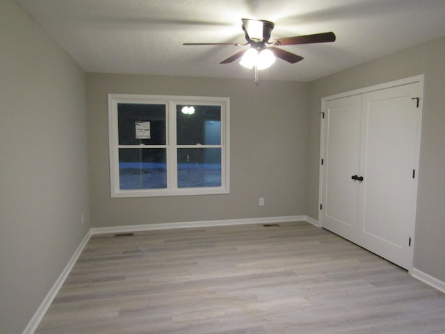 unfurnished bedroom featuring a closet, baseboards, ceiling fan, and light wood finished floors