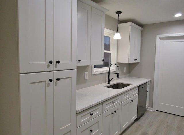 kitchen featuring dishwasher, white cabinetry, light countertops, and a sink