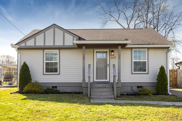 view of front of house with fence, roof with shingles, a front lawn, a carport, and crawl space