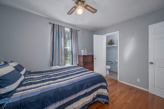 bedroom with a ceiling fan, ensuite bathroom, baseboards, and wood finished floors