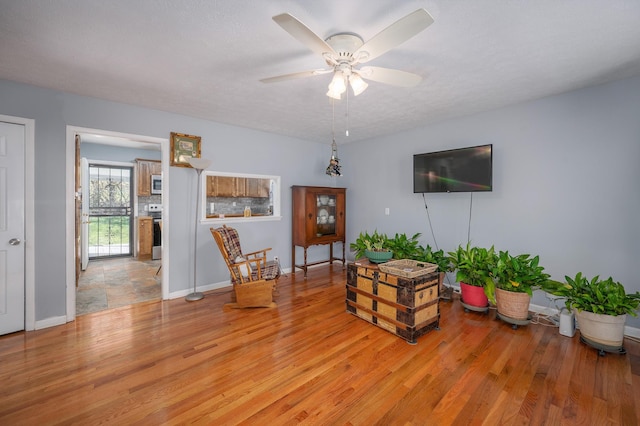 sitting room with light wood-type flooring, baseboards, and a ceiling fan