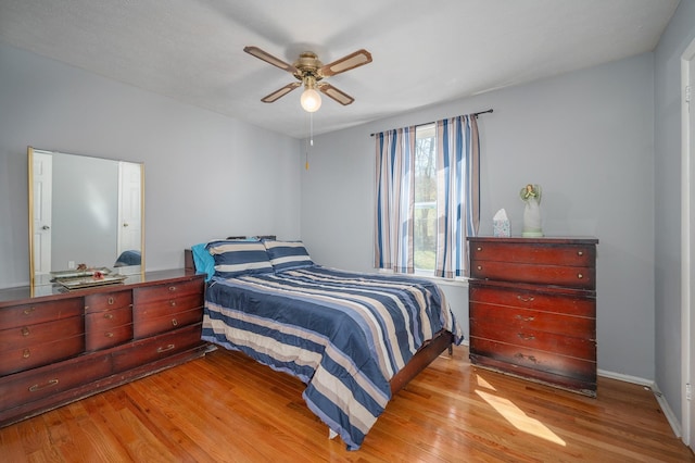 bedroom with light wood-style flooring, a ceiling fan, and baseboards