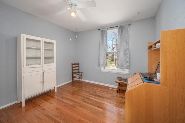 unfurnished room featuring ceiling fan, visible vents, baseboards, and wood finished floors