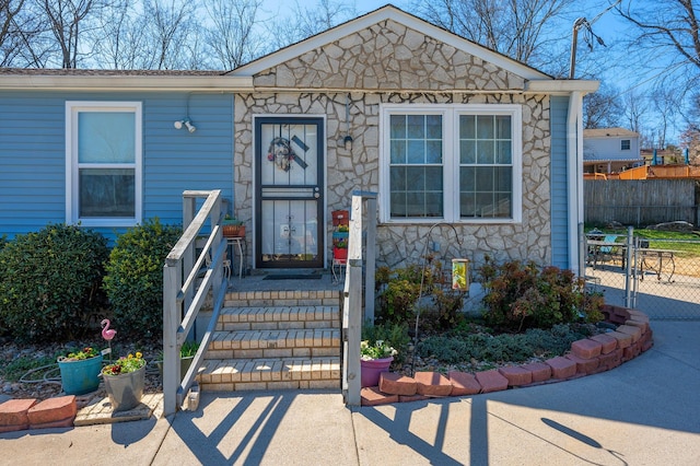 view of front of home featuring stone siding, fence, and a gate