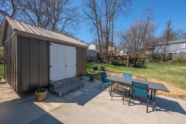 view of patio / terrace with an outbuilding, outdoor dining area, a fenced backyard, entry steps, and a storage unit