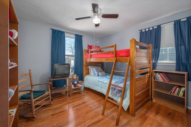 bedroom with a textured ceiling, a ceiling fan, and wood finished floors