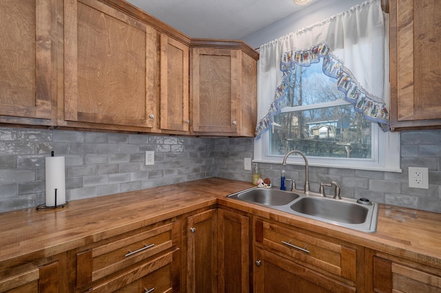 kitchen with tasteful backsplash, brown cabinets, wooden counters, and a sink