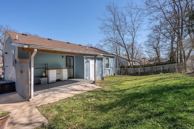 back of property with fence, a lawn, and roof with shingles