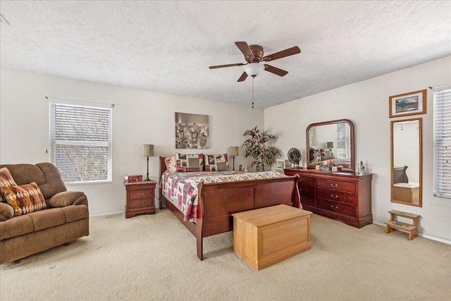 bedroom featuring light carpet, baseboards, a textured ceiling, and ceiling fan