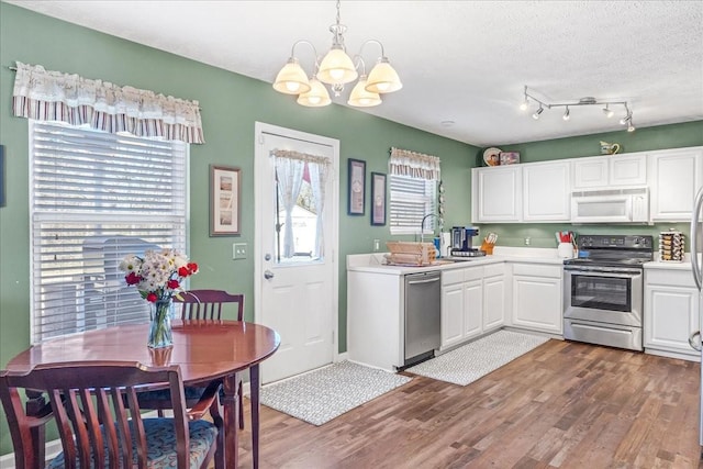 kitchen featuring light countertops, appliances with stainless steel finishes, wood finished floors, white cabinets, and a textured ceiling