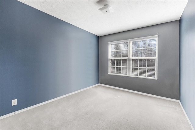 carpeted spare room featuring baseboards and a textured ceiling