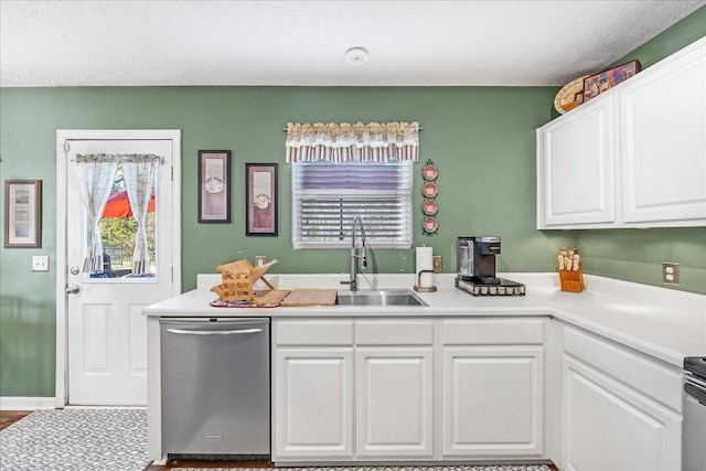 kitchen featuring stainless steel dishwasher, light countertops, white cabinets, and a sink