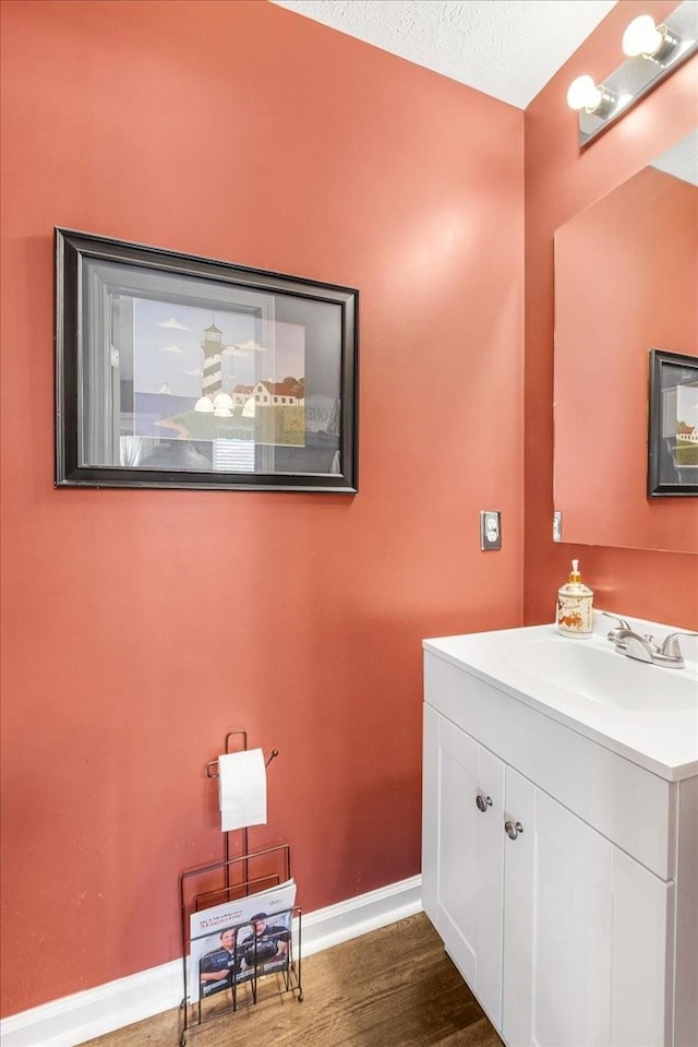 bathroom featuring baseboards, wood finished floors, and vanity