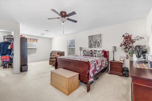 bedroom featuring a textured ceiling, a ceiling fan, visible vents, and light carpet