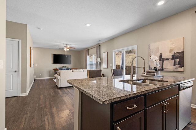 kitchen featuring stainless steel dishwasher, dark brown cabinetry, open floor plan, and a sink