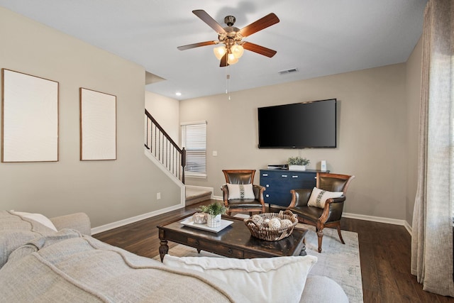 living room featuring stairway, baseboards, visible vents, and wood finished floors