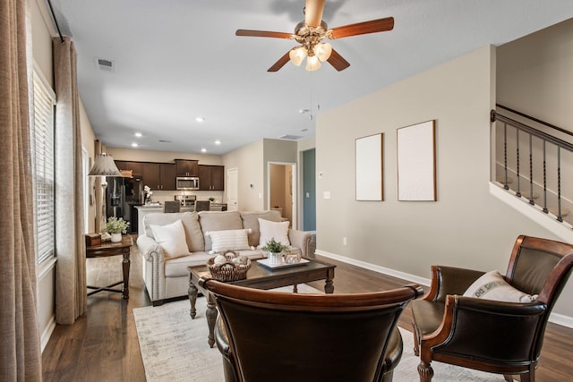 living area featuring dark wood-type flooring, stairway, visible vents, and baseboards