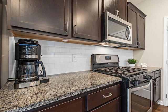 kitchen featuring tasteful backsplash, dark brown cabinets, appliances with stainless steel finishes, and dark stone counters