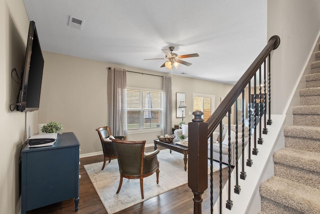 stairway featuring baseboards, a textured ceiling, wood finished floors, and a ceiling fan