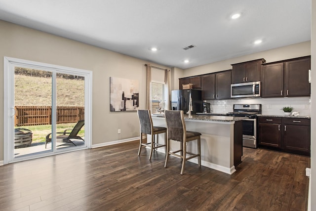 kitchen featuring visible vents, backsplash, a kitchen bar, a wealth of natural light, and stainless steel appliances