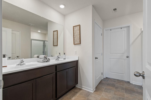 full bath featuring a sink, baseboards, a stall shower, and double vanity