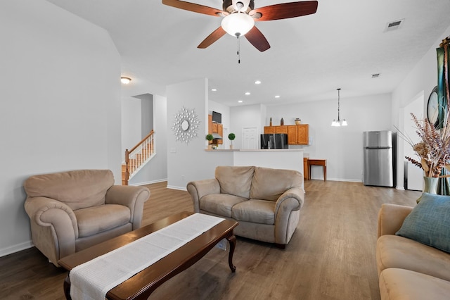 living room featuring visible vents, stairway, light wood-type flooring, and baseboards