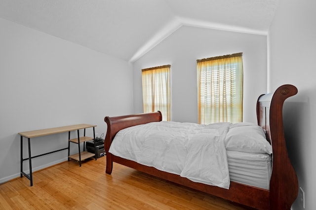 bedroom with baseboards, wood finished floors, and vaulted ceiling