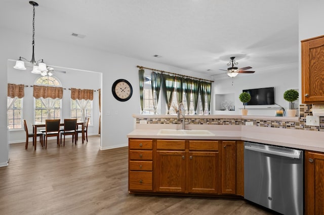 kitchen featuring visible vents, a sink, backsplash, stainless steel dishwasher, and brown cabinetry