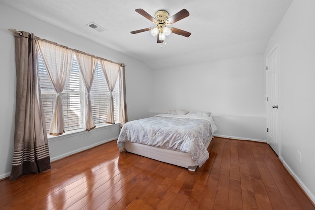 bedroom with hardwood / wood-style floors, multiple windows, baseboards, and visible vents