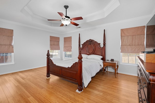 bedroom featuring visible vents, crown molding, a raised ceiling, and light wood-style floors