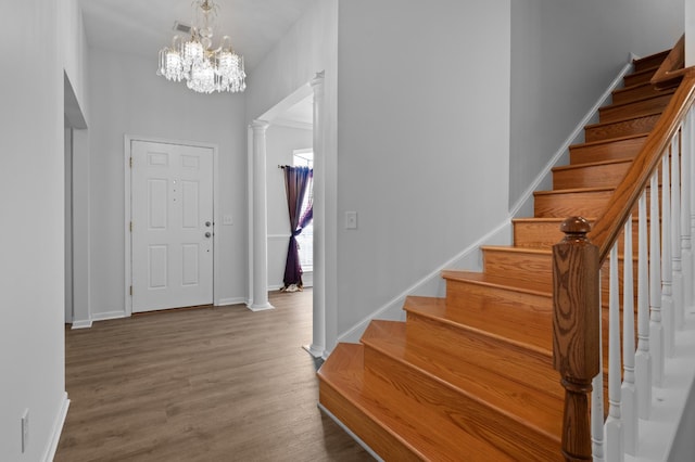 foyer entrance with stairs, decorative columns, wood finished floors, and baseboards