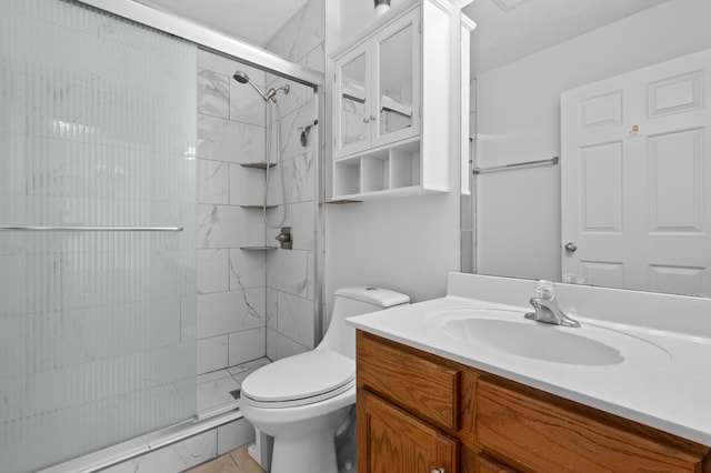 bathroom with vanity, a shower stall, and toilet