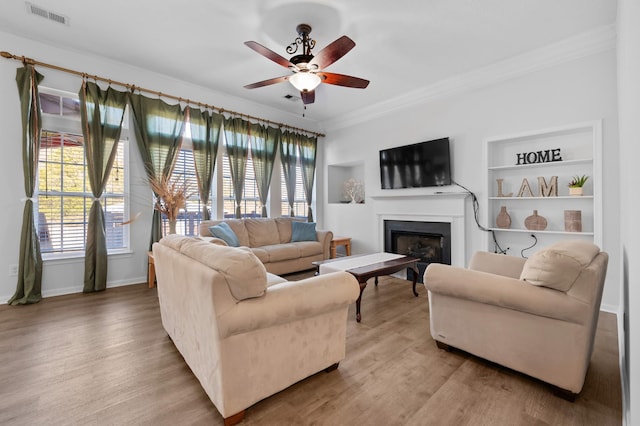 living area featuring crown molding, wood finished floors, visible vents, and a wealth of natural light