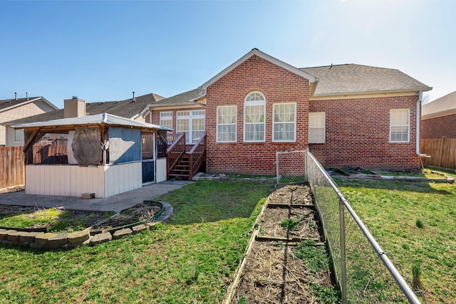 back of house with a vegetable garden, a yard, a fenced backyard, and brick siding