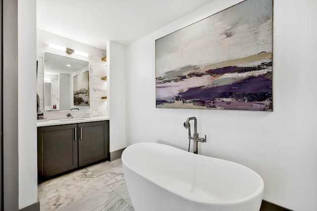 full bathroom with marble finish floor, vanity, and a freestanding tub