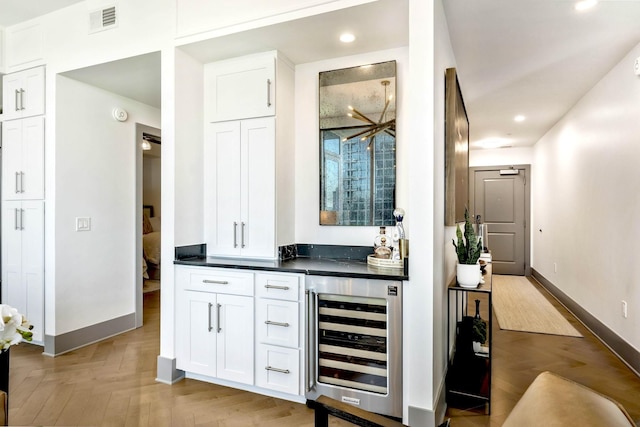 bar featuring beverage cooler, visible vents, baseboards, recessed lighting, and parquet floors