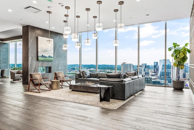 living area with a view of city, floor to ceiling windows, wood finished floors, and visible vents