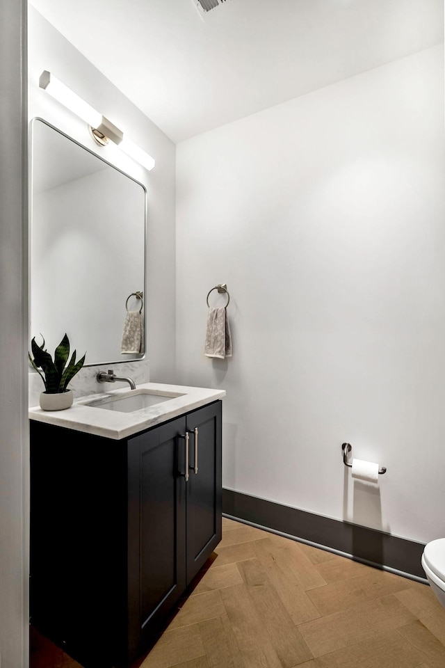 bathroom with vanity, toilet, and baseboards