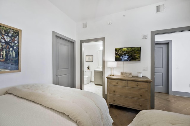 bedroom with dark wood-type flooring, baseboards, visible vents, and ensuite bathroom