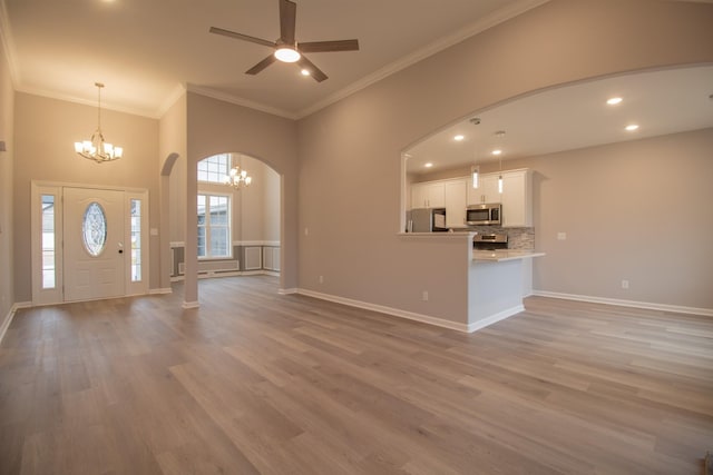 foyer featuring baseboards, arched walkways, crown molding, and light wood finished floors