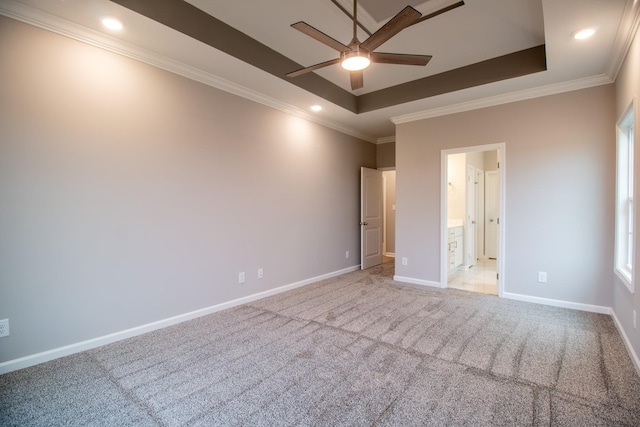 unfurnished bedroom with light colored carpet, a raised ceiling, and baseboards