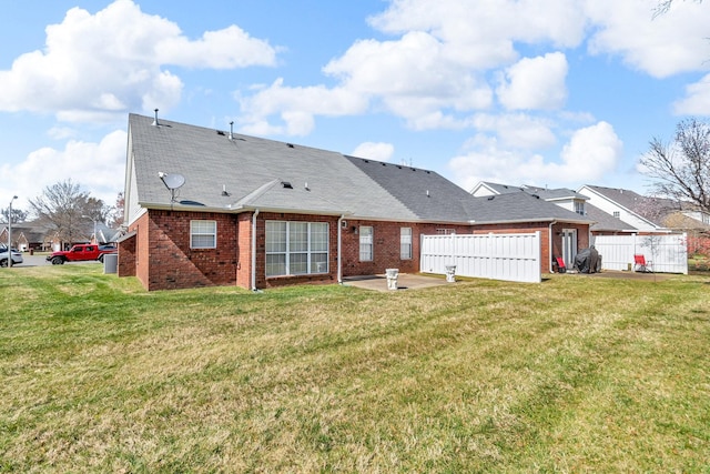 back of house featuring a yard, a patio area, fence, and brick siding