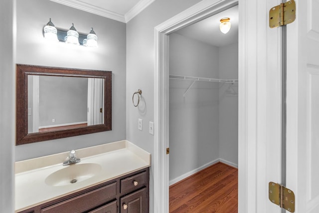 bathroom featuring crown molding, baseboards, vanity, and wood finished floors